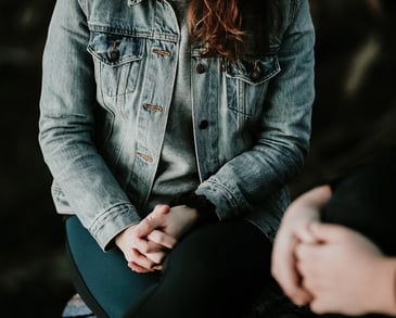 A person sitting with hands clasped having Therapy session